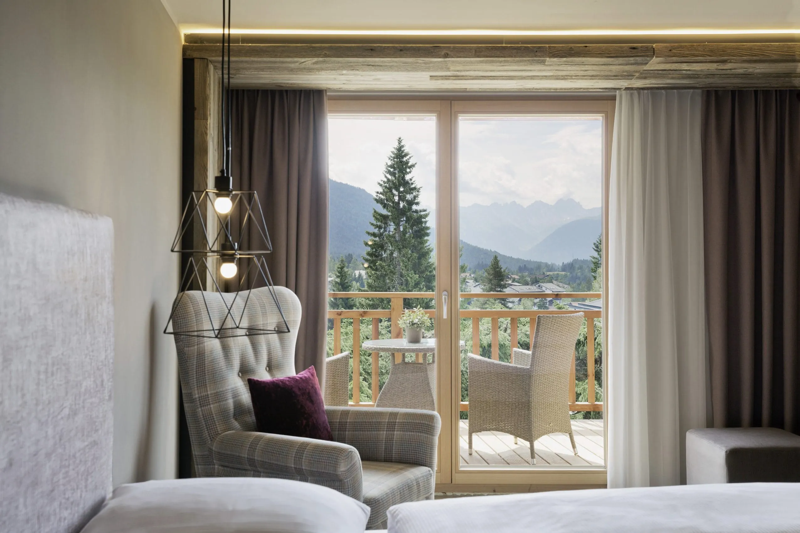 Blick vom einem Zimmer des Wellnesshotels L&auml;rchenhof auf den Balkon und die Berglandschaft im Hintergrund.