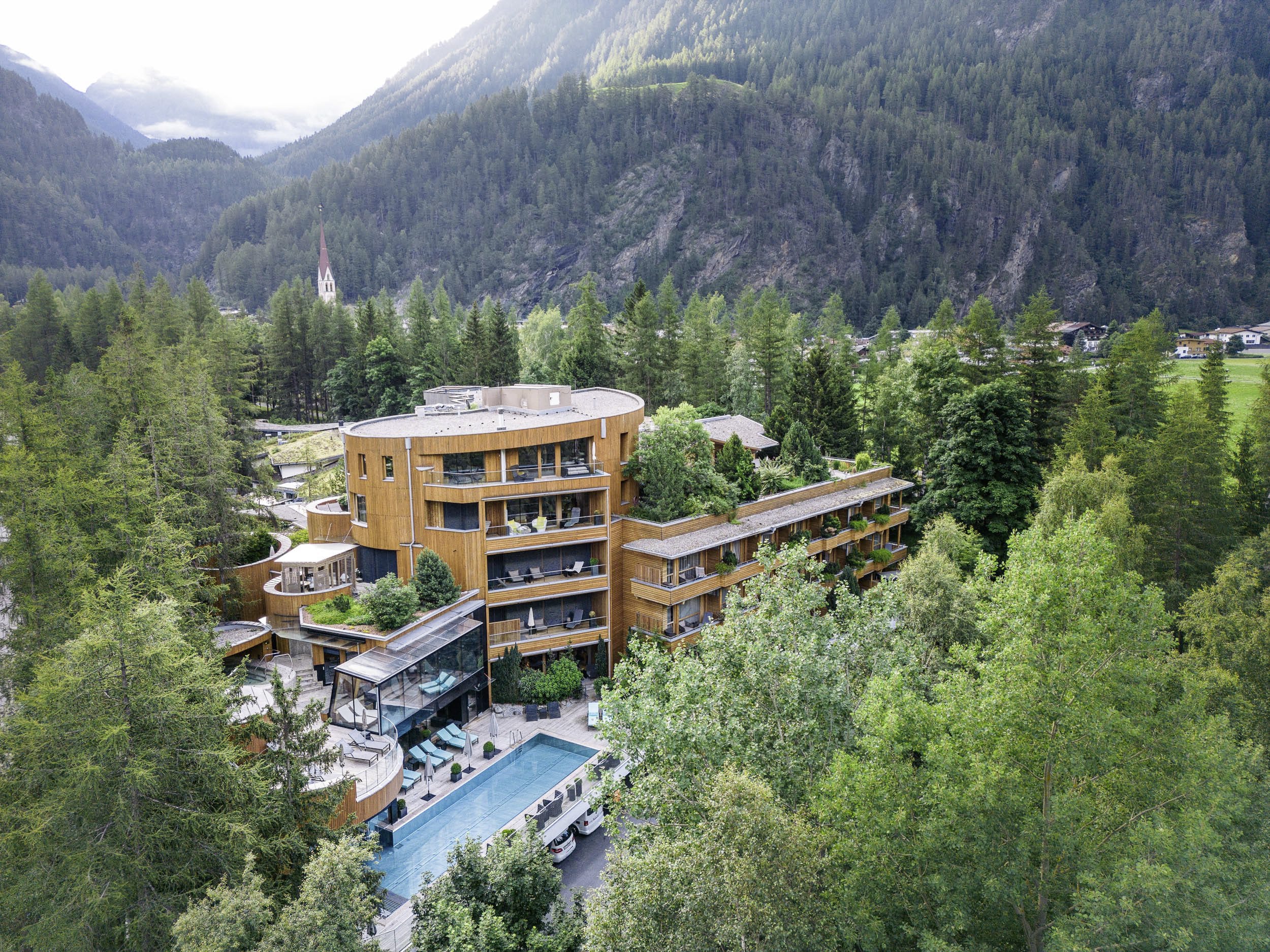 Außenansicht des Naturhotels Waldklause, das sich mit seiner durchgehenden Holzfassade perfekt in den umliegenden Wald einschmiegt.