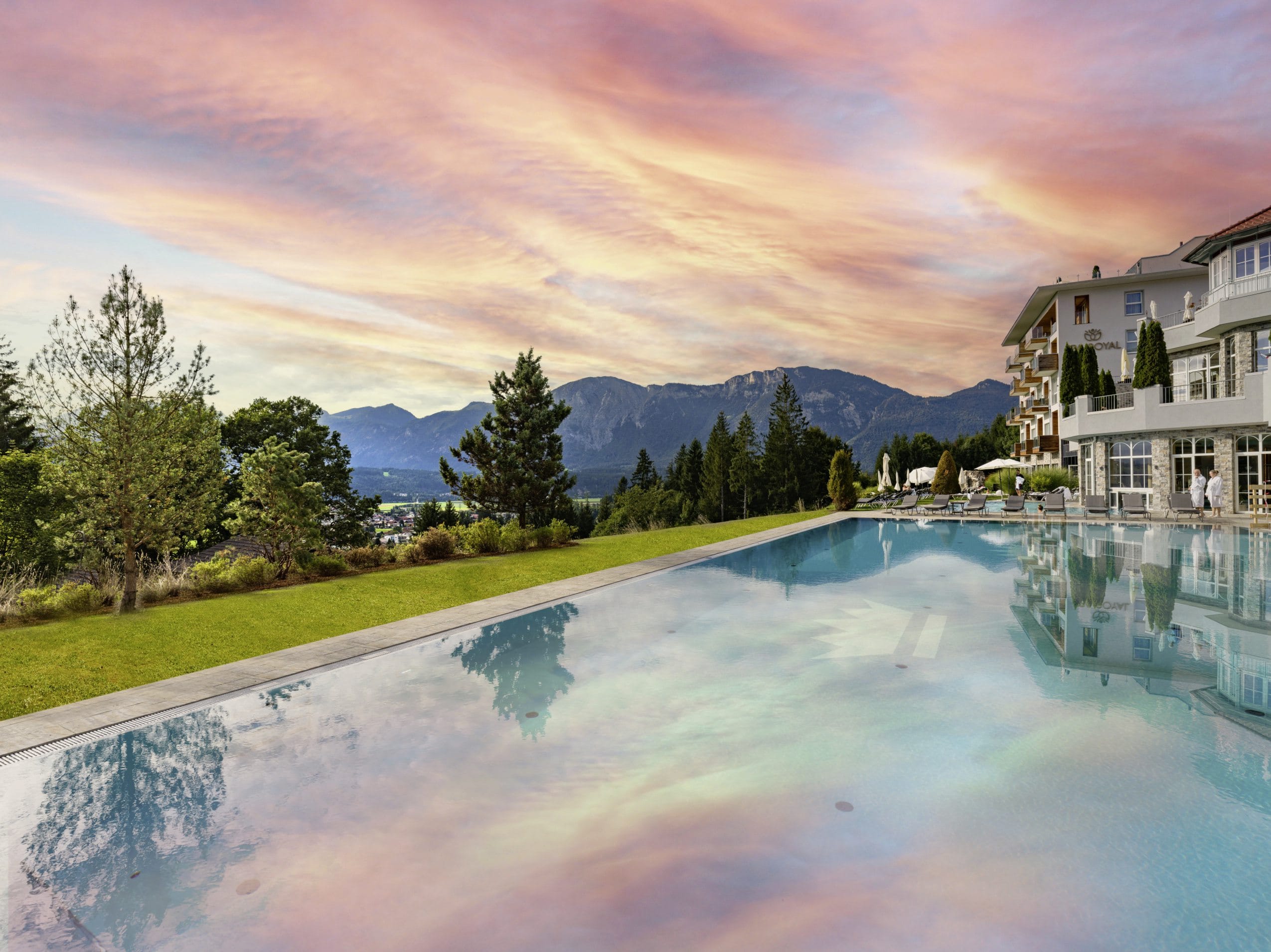 Der rot-blaue Sonnenuntergang spiegelt sich malerisch im Außenpool des Panorama Royal Wellnesshotels in Tirol.