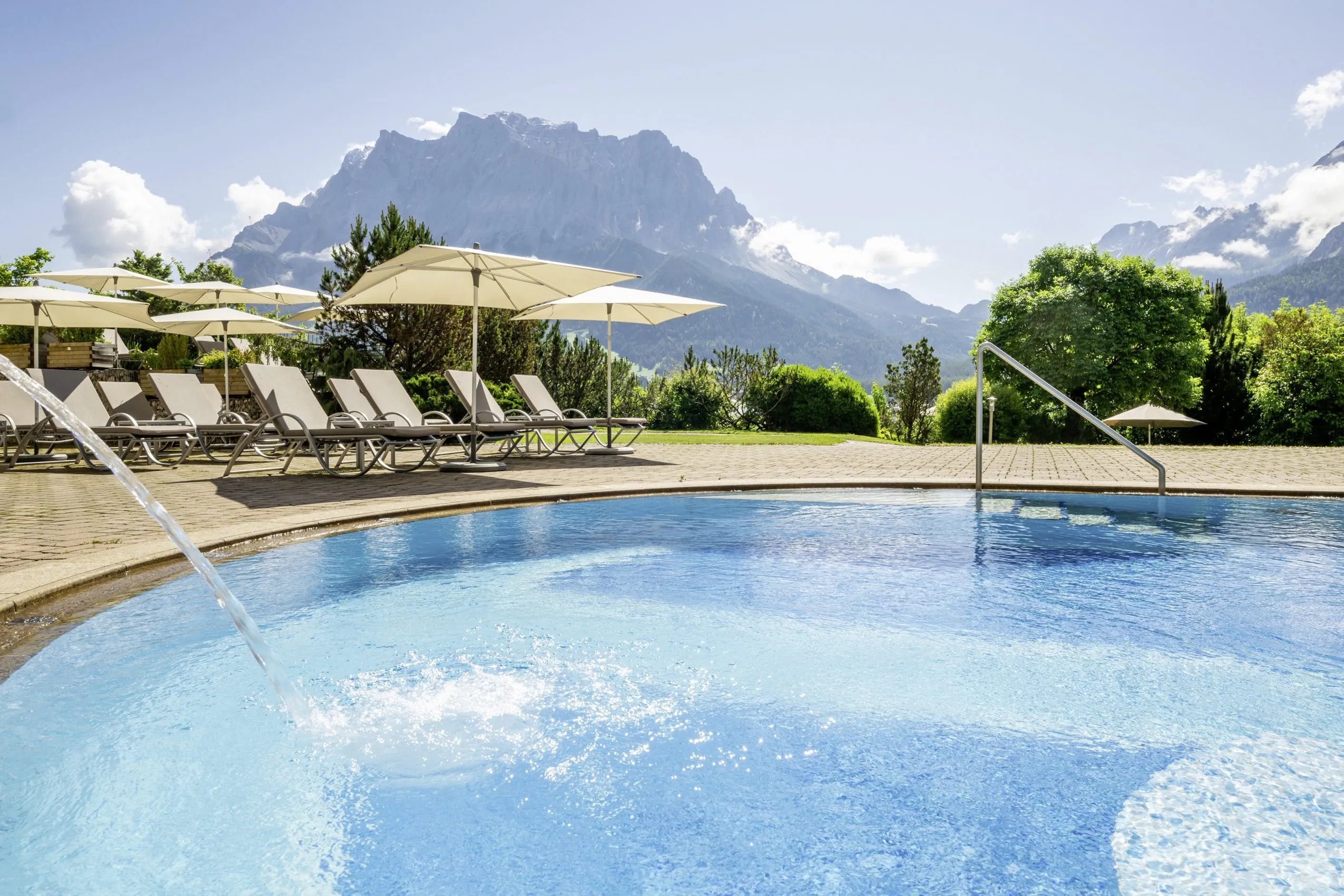 Strahlend t&uuml;rkisblauer Pool mit Blick auf die Tiroler Gebirge vom Wellnesshotel Post Lermoos aus.