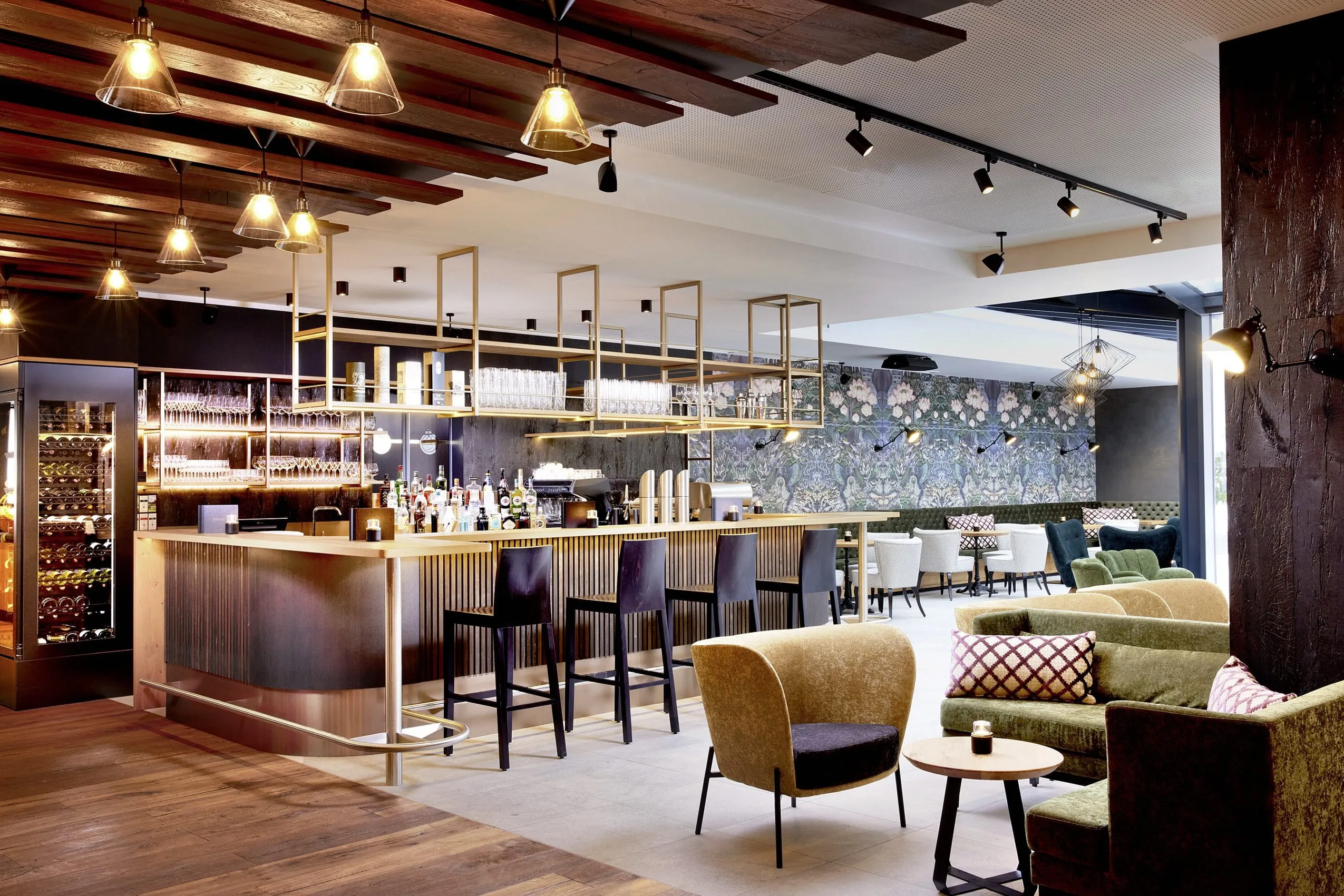 Ein echter Hinkucker ist ist die Bar des SeeMOUNT Wellnesshotels in Tirol. Bunte Blumentapeten und Sessel treffen auf modernen chic in Holz und Metal.