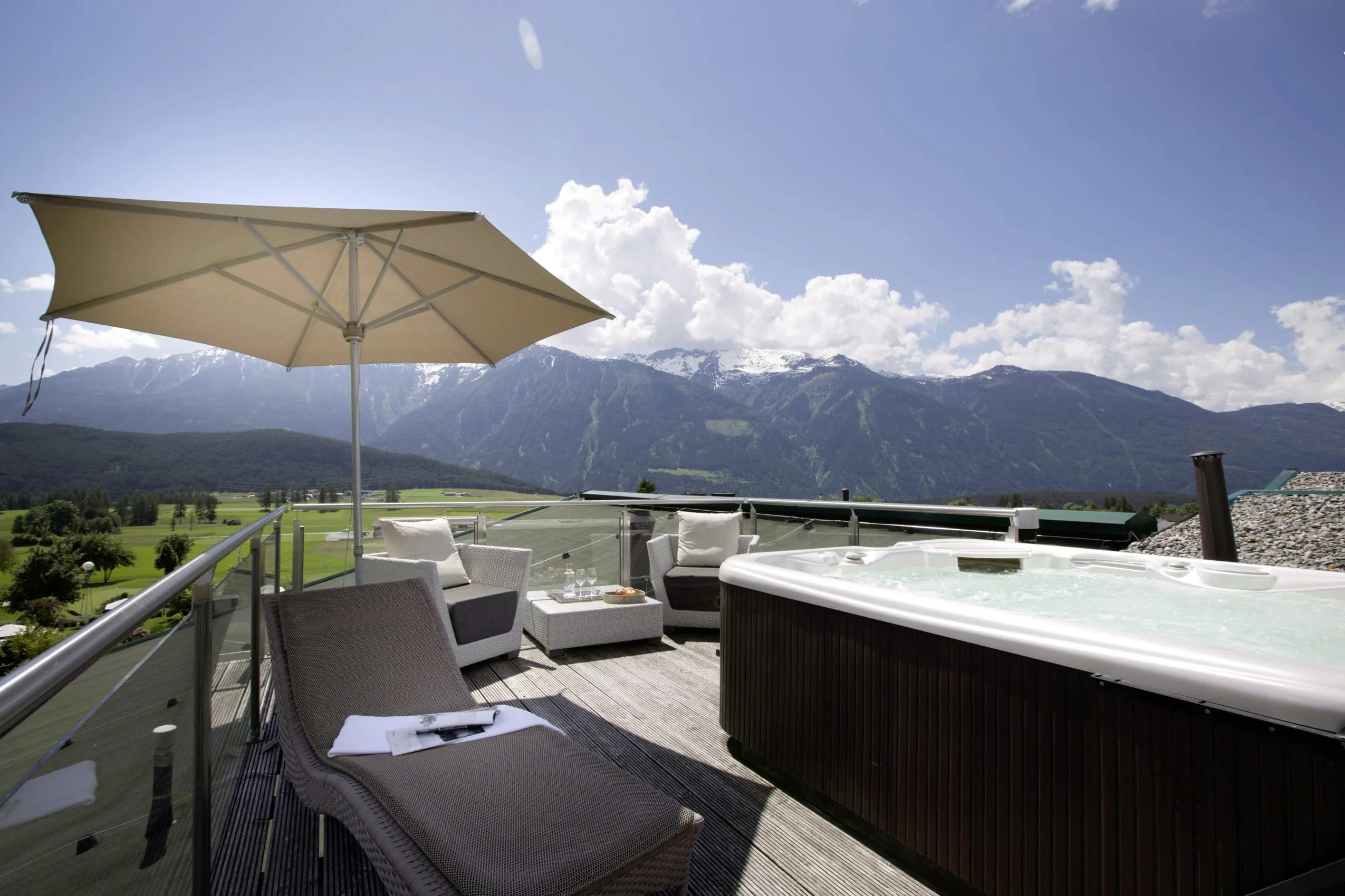 Whirlpool auf der Terrasse mit atemberaubendem Ausblick auf die Berge. Daneben befinden sich Sessel und Liegen zum entspannen.