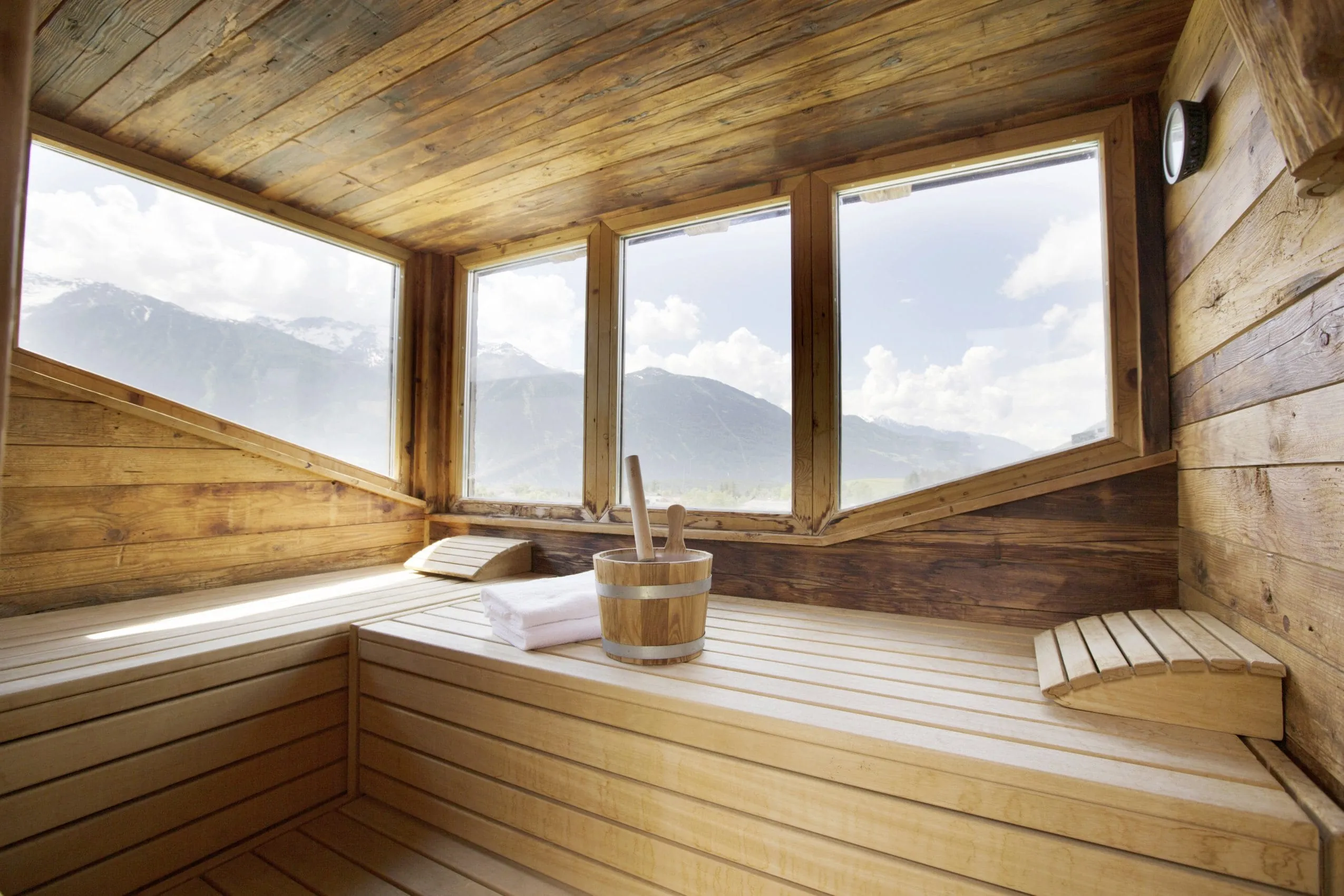Holzsauna mit Aufgussk&uuml;bel und Panoramafenster auf die Berge.