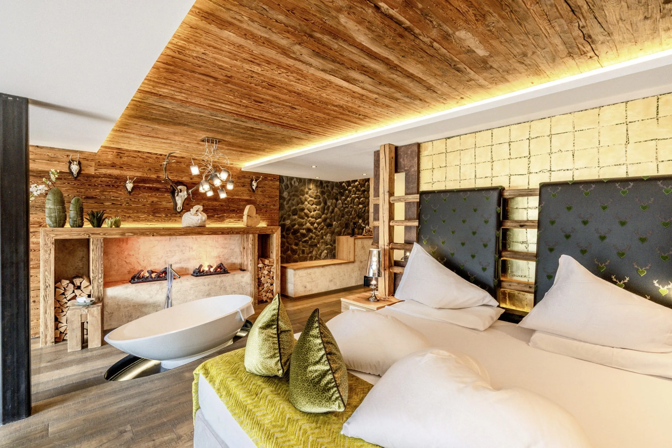 Privat Wellness Suite des Andreas Golf Resort & Spa, die rustikal eingerichtet ist und eine freistehende Badewanne neben dem Bett hat.