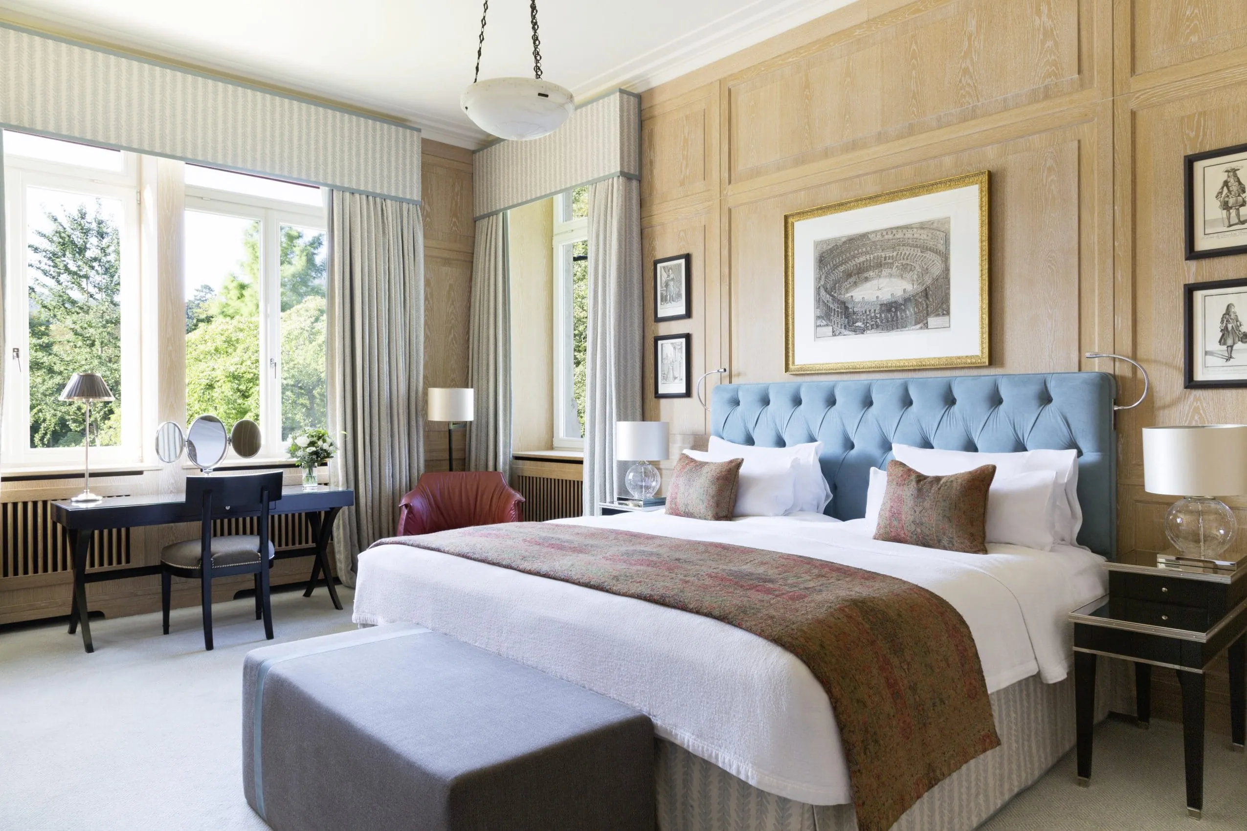 Schlafzimmer mit Holz-Dekor-Vert&auml;felung, Boxspringbett und schwarzem Schminktisch.