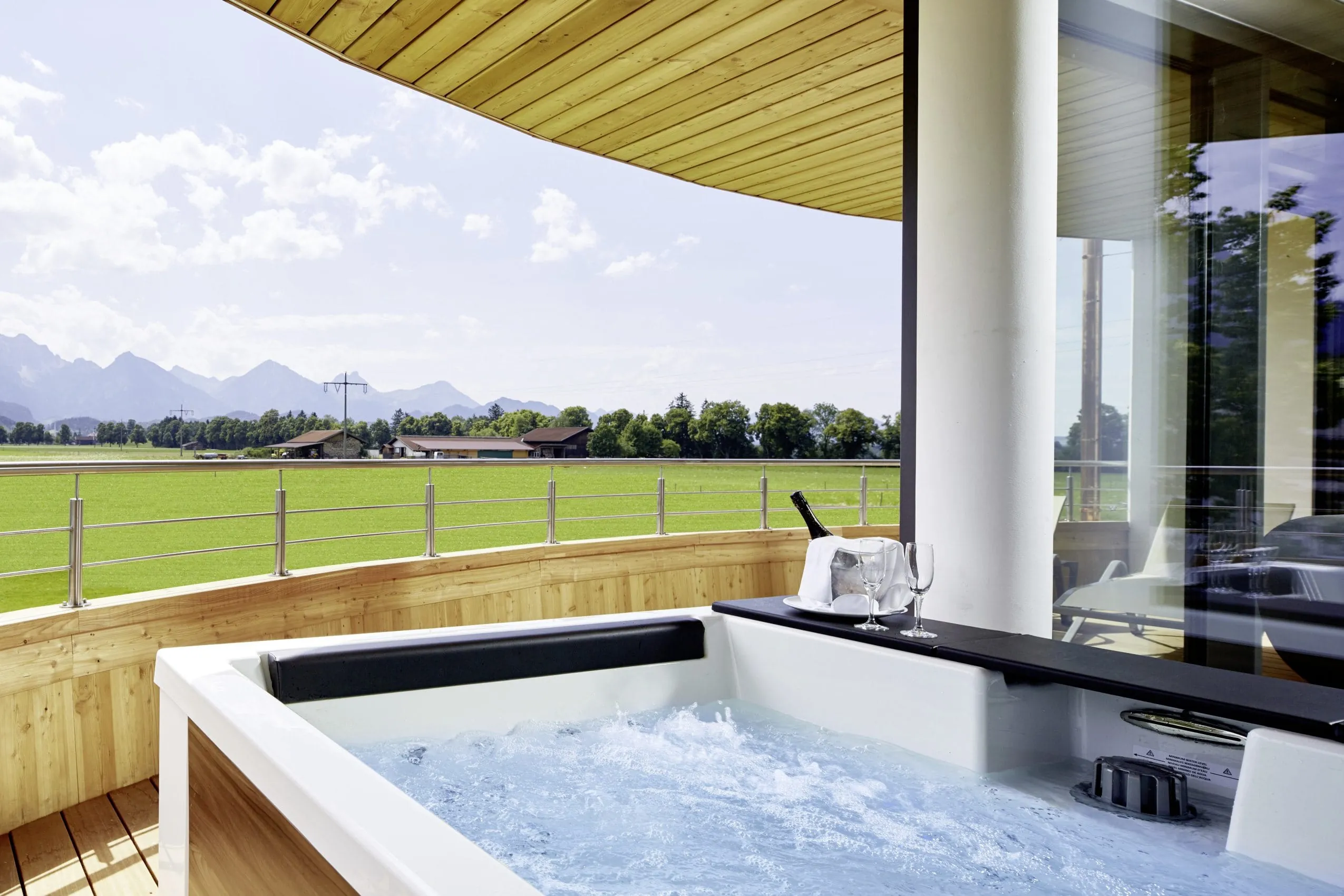 &Uuml;berdachte Holz-Terrasse mit Whirlpool und Blick auf die umliegenden Berge.