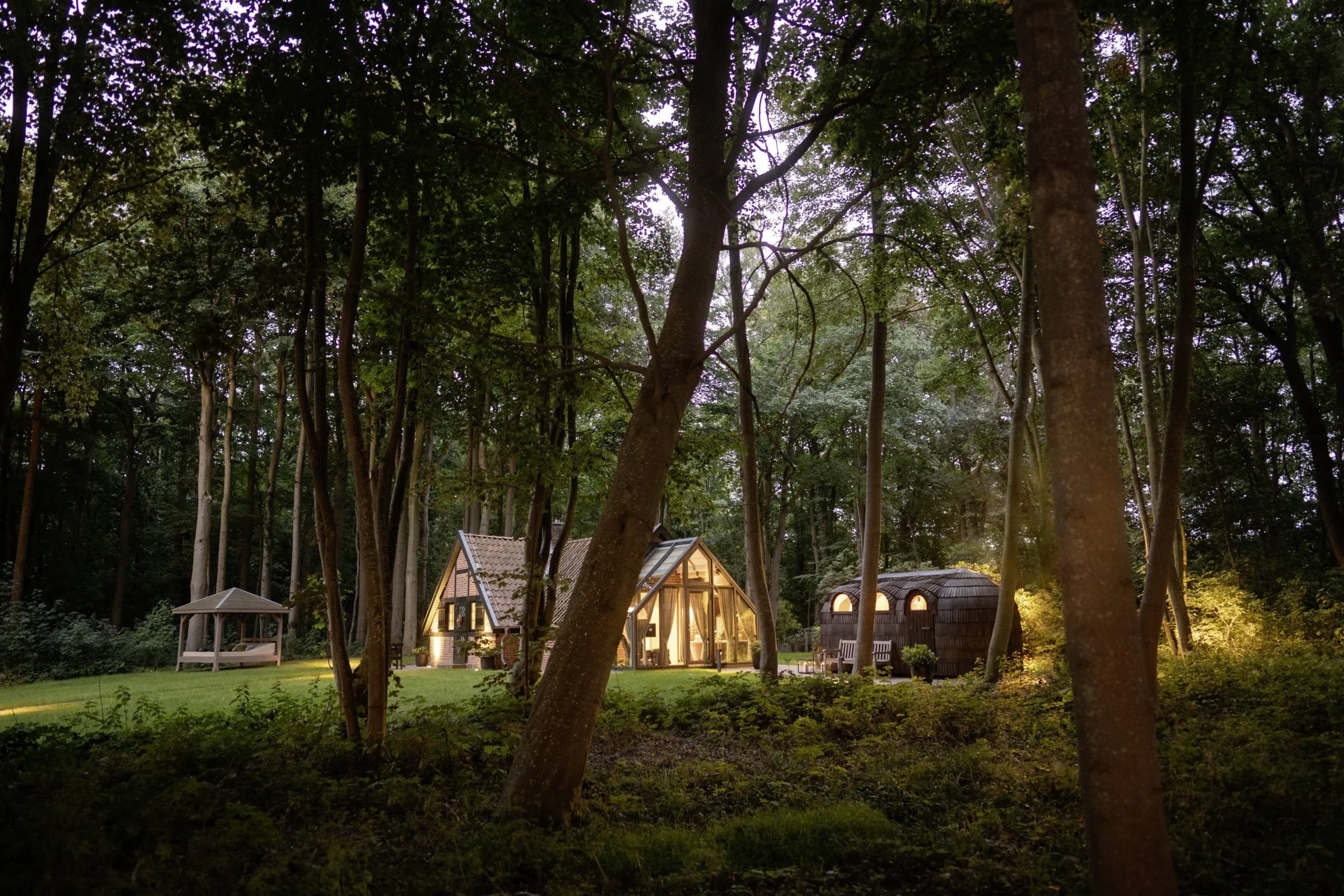 Blick auf das beleuchtete Private Cottage des WEISSENHAUS Private Nature Luxury Resort im Wald