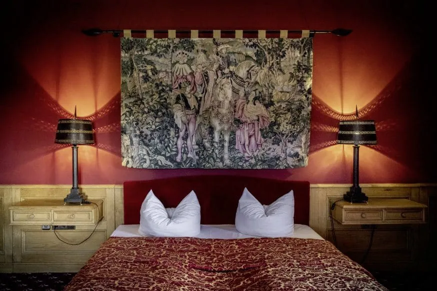 Prunkvolles Doppelzimmer in Rot mit altert&uuml;mlichem Wandteppich und roter Samt Tagesdecke