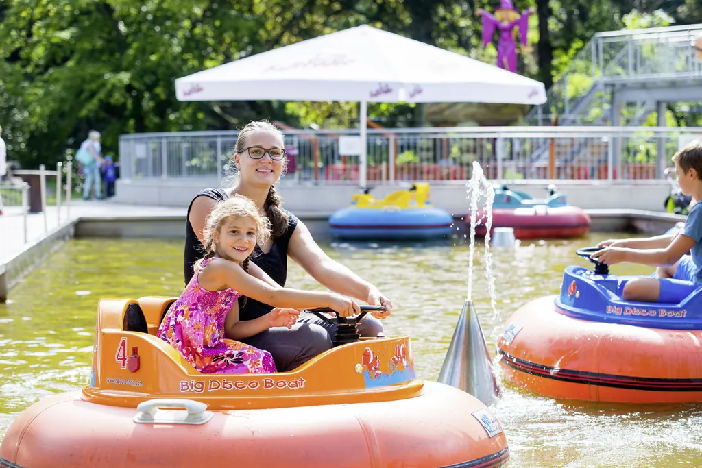 Mutter und Tochter in einem Bumper Boat, die in die Kamera lächeln in der tollen Unternehmung für Kinder, der Seilbahn Thale Erlebniswelt.