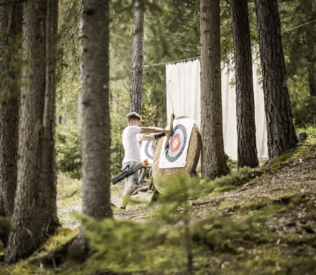 Junge zieht Pfeil aus der Zielscheibe beim Bogenschießen im Excelsior Dolomites Life Resort