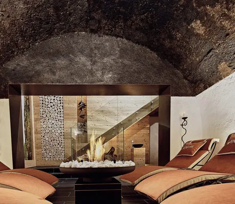 Ruheraum im Gewölbe des Hotel Traube mit roten Liegen und Feuerschale im Zentrum