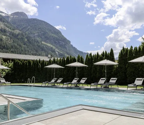 Outdoorpool im Hotel Traube mit weißen Sonnenschirmen und Blick auf die Berge