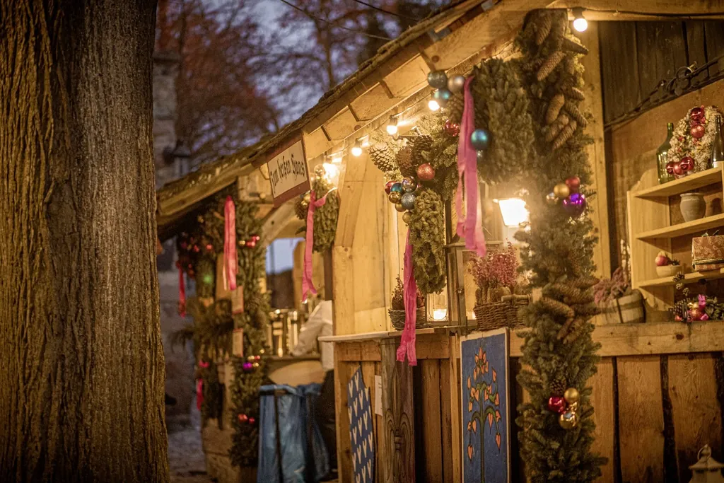 mit Kugeln und Tannenzweigen/-zapfen weihnachtlich geschm&uuml;ckte und beleuchtete St&auml;nde auf dem Weihnachtsmarkt auf der Leuchtenburg