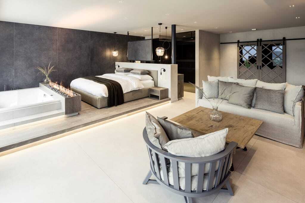 Suite im PURMONTES Private Luxury Chalet mit Leinensofa und im Wohnbereich integrierter Wanne