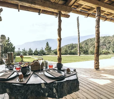 Gedeckter Frühstückstisch auf der großen Terrasse des Chalet Resort ZU KIRCHWIES mit freiem Blick auf Bäume und Berge