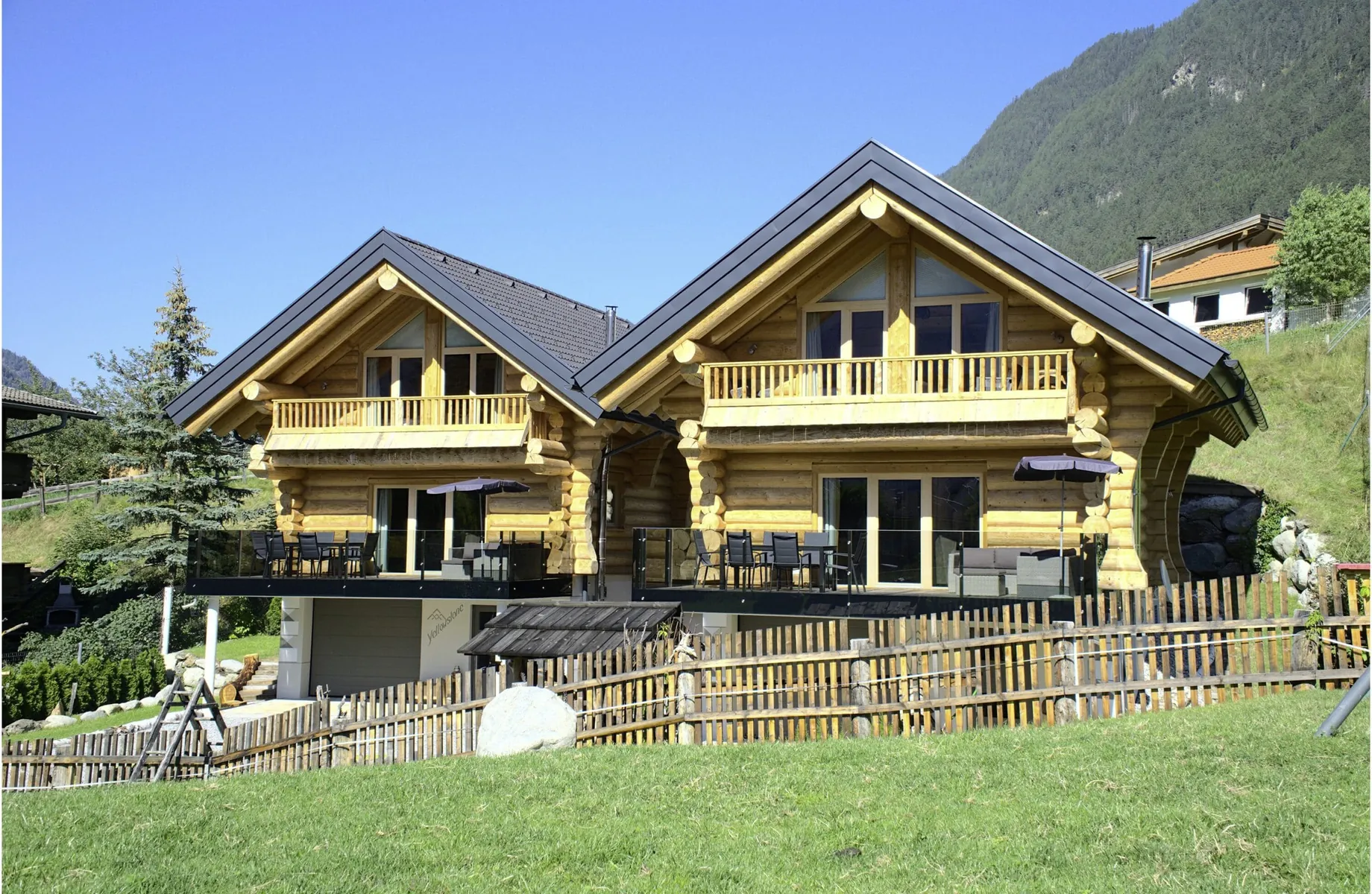 Außenansicht der Summit Lodges im Blockhaus-Stil, jeweils mit Terrasse und Balkon bei strahlend blauem Himmel