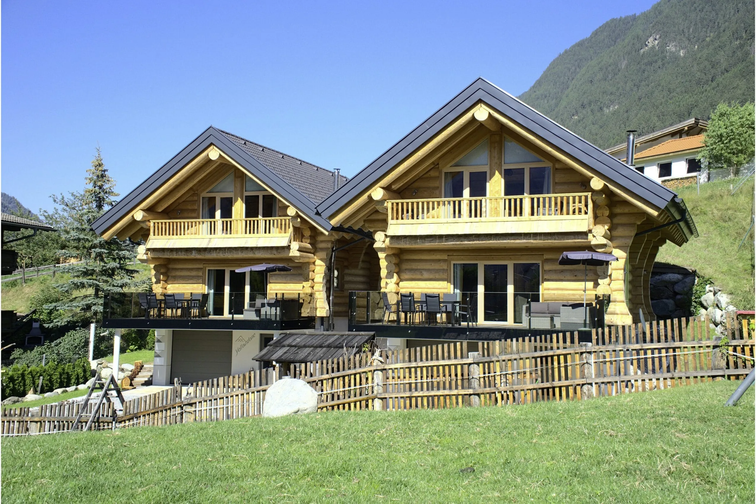 Außenansicht der Summit Lodges im Blockhaus-Stil, jeweils mit Terrasse und Balkon bei strahlend blauem Himmel