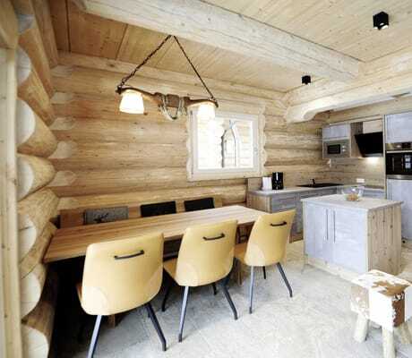 Blick in den Essbereich der Summit Lodges mit Esstisch, Stühlen und Küche aus Holz mit grauen Türen