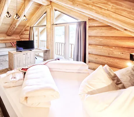 obere Etage der Summit Lodges mit Holzwänden, Doppelbett, kleinem Fernseher, großem Holzschrank und grauem Sofa im Hintergrund