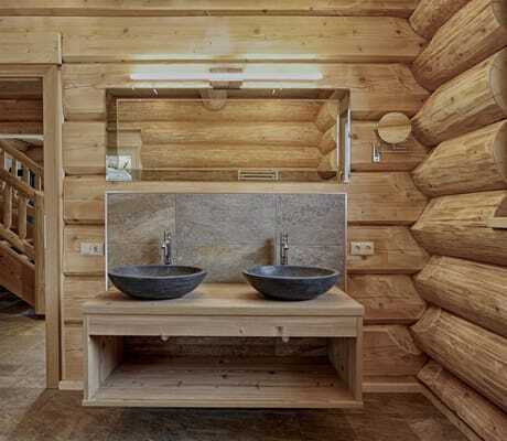 Badezimmer der Summit Lodges mit Holzwänden, zwei dunkelgrauen Stein-Waschbecken, Spiegel und Steinfliesenboden
