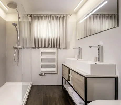 helles Badezimmer im Chalet vue au lac mit großer Regendusche, zwei Waschbecken, beleuchtetem Spiegel und dunklem Holzboden