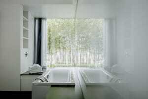 weiß eingerichtetes Badezimmer mit Badewanne und großem Fenster mit Blick ins Grüne auf dem Hofgut Hafnerleiten