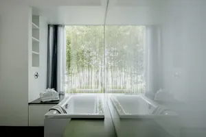 weiß eingerichtetes Badezimmer mit Badewanne und großem Fenster mit Blick ins Grüne auf dem Hofgut Hafnerleiten