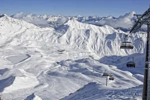 verschneite Berglandschaft mit Sessellift, Skipisten und schneebedeckten Gipfeln in der Nähe der Summit Lodges