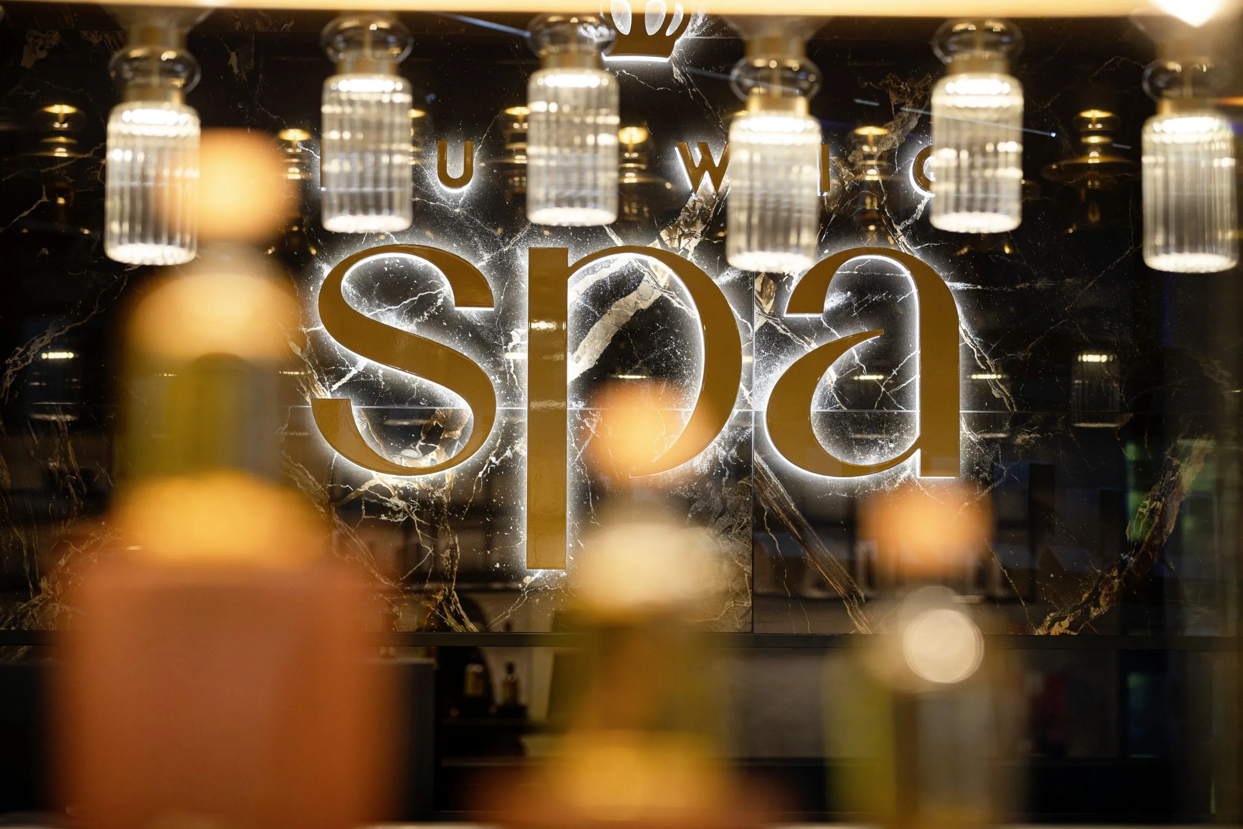 Spa-Rezeption im Wellnesshotel K&ouml;nig Ludwig mit beleuchtetem Schriftzug an der Wand