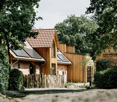 Blick auf das Gelände des Familotel Landhaus Averbeck mit Holz- und Klinkersteingebäuden umgeben von vielen Bäumen