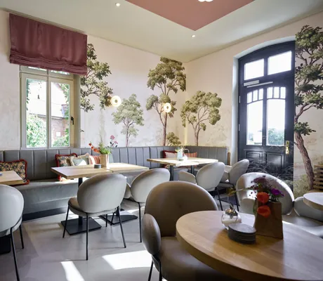 Restaurant des Familotel Landhaus Averbeck mit grauen Stühlen und Sitzbänken, Holztischen und Baummalerei an den Wänden