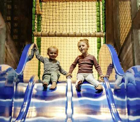 zwei Kinder sitzen nebeneinander auf einer blauen Rutsche des Familotel Landhaus Averbeck