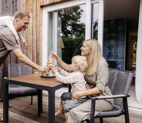 Familie stößt mit ihren Getränken auf der Terrasse ihres Hotelzimmers des Familotel Landhaus Averbeck an