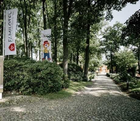 schmaler Weg mit Hotelschild umgeben von Bäumen, der zum Familotel Landhaus Averbeck führt