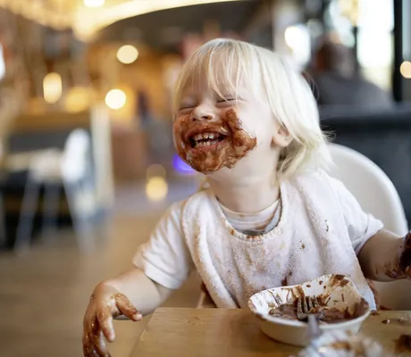 blondes Kind mit komplett verschmiertem Schokomund sitzt im Landhaus Zur Ohe am Tisch