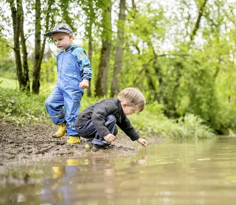 zwei Jungs in Matschhosen spielen im Wald des Landhaus Zur Ohe am Bach