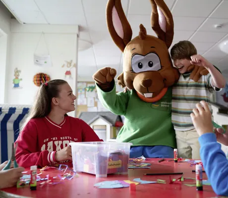 Im Kinderclub des Weissenhäuser Strand umarmt ein Junge das Maskottchen und streckt die Faust in die Höhe