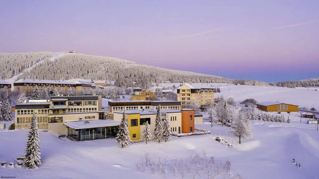 Luftaufnahme der verschiedenen Gebäude des Familotel Elldus Resort im Winter mit schneebedeckten Feldern und Bäumen