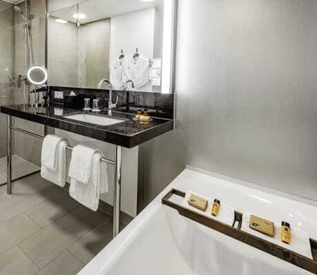 Badezimmer mit schwarzem Waschtisch und Badewanne im Hotel 47°