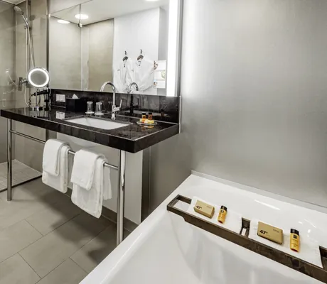 Badezimmer mit schwarzem Waschtisch und Badewanne im Hotel 47°