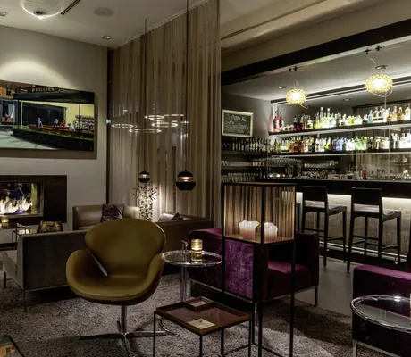gemütliche Bar im Hotel 47° mit Kaminfeuer und edlen beigen und roten Sofas und Sesseln
