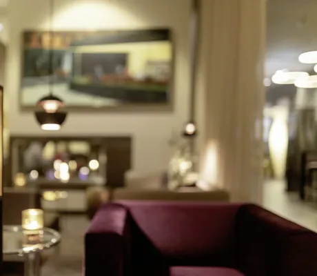 Detailaufnahme einer goldenen Lampe neben einem roten Sofa im Hotel 47°