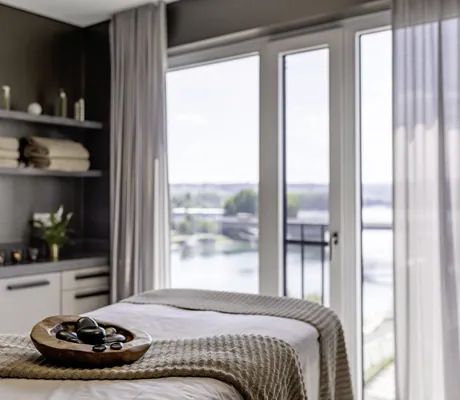 Behandlungsraum im Hotel 47° mit Holzschale mit Steinen auf der Liege und Blick auf den Seerhein