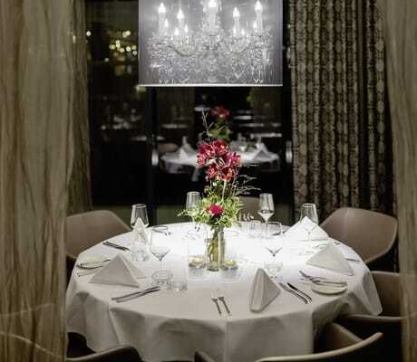 festlich eingedeckter runder Tisch im Restaurant des Hotel 47° mit goldenen Vorhängen