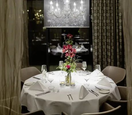 festlich eingedeckter runder Tisch im Restaurant des Hotel 47° mit goldenen Vorhängen