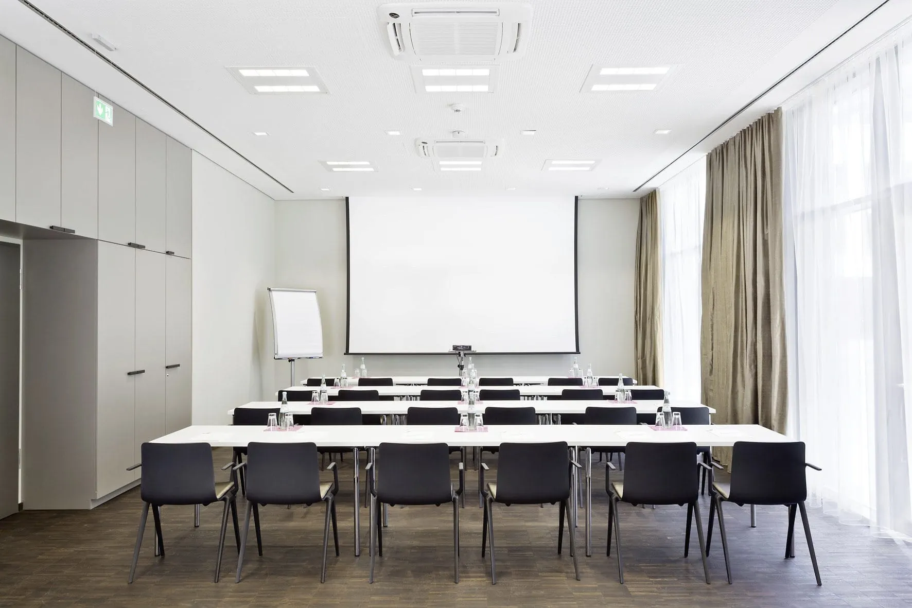 Stuhlreihen im Tagungsraum des Hotel 47&deg; mit Leinwand und Flipchart