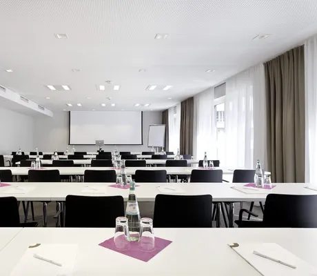 Reihenbestuhlung im großen Tagungsraum des Hotel 47° mit heruntergelassener Leinwand