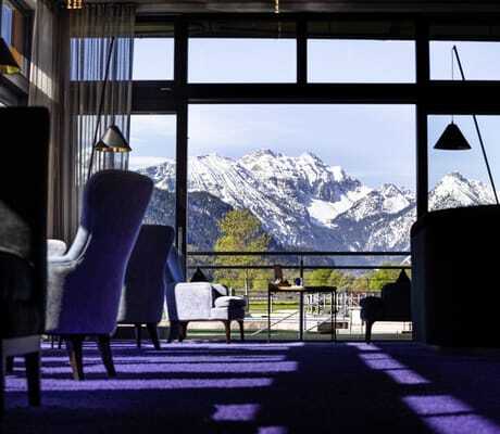 Bar im Das König Ludwig Inspiration SPA mit großen Ohrensesseln und Blick auf die verschneiten Berge