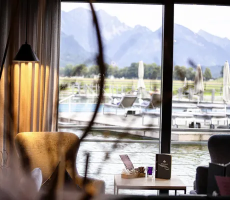 Blick von der Bar im Das König Ludwig Inspiration SPA auf den Schwanensee mit Liegen und Sonnenschirmen