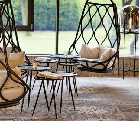 Rohr-Hängesessel mit schwarzen runden Beistelltischen im Das König Ludwig Inspiration SPA